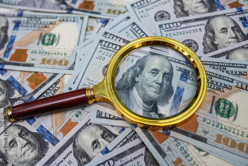 Golden Magnifying Glass on US Dollar Banknotes for Detailed Financial Audit and Tax Inspection