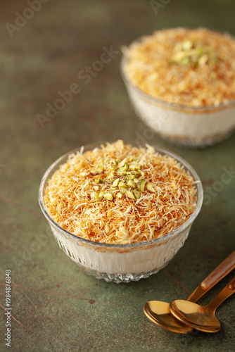 Traditional milky crispy Ramadan dessert custard pudding with roasted kadayif and diced pistachio . Kadayifli Muhallebi