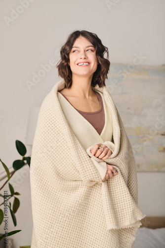 Foto Charming woman enjoying a cozy moment at home wrapped in a warm blanket