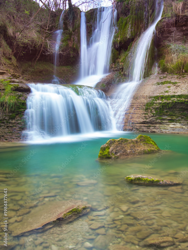Obraz premium Long-exposure shot of the stunning multiple waterfalls and turquoise pool at the Peña Ladros Natural Monument, showcasing the power and beauty of flowing water.