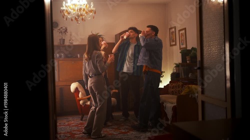 Cheerful Group Of People Toasting Beverages Amid Lively Music And Joyful Dancing In Cozy Kitchen