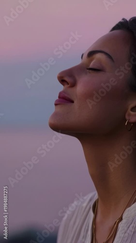 Beautiful woman meditating with her eyes closed, finding peace and tranquility while enjoying the calm moment and breathing fresh air in nature during a beautiful pastel colored sunset