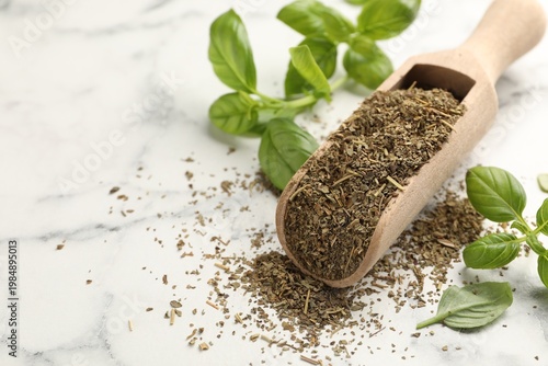 Dry basil, scoop and fresh leaves on white marble table, closeup. Space for text