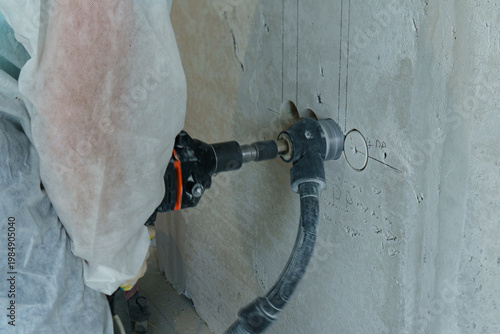 Foto Electrician chasing wiring in a concrete wall at a construction site