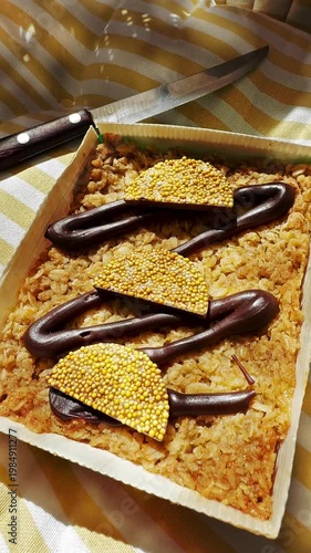 Vertical video social media - Closeup of a decorative chocolate orange flavor flapjack dessert (made with oats and syrup), on a chair cushion, with a knife, ready to cut and eat.
