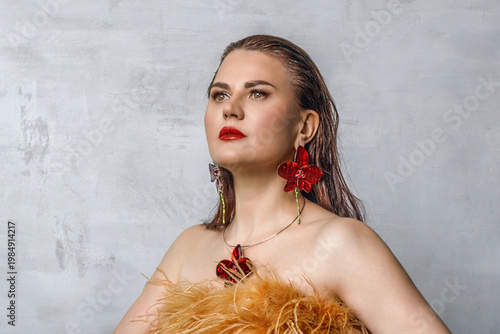 Portrait of a beautiful brunette with long hair in a golden evening dress with fur and red satin long gloves on her hands.
