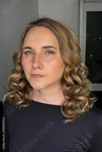 Portrait of a young blonde woman with curly hair on a dark background