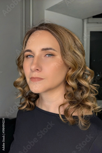 Portrait of a young blonde woman with curly hair on a dark background