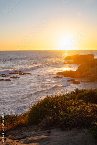 High angle view of sunset over the sea with waves washing up to rocky shoreline 