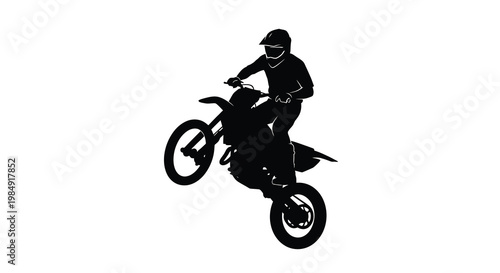 Silhouette of a motorcyclist performing a wheelie on a dirt bike
