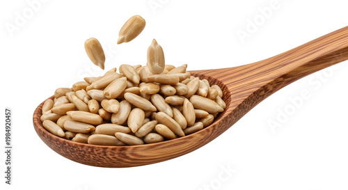 Peeled sunflower seeds in wooden spoon, organic hulled sunflower kernels falling into spoon, healthy snack ingredients on white background