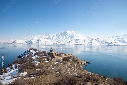 View of Akdamar Island with Holy Cross Church, Lake Van and snow-covered mountains, highlighting cultural heritage and winter landscape in eastern Türkiye