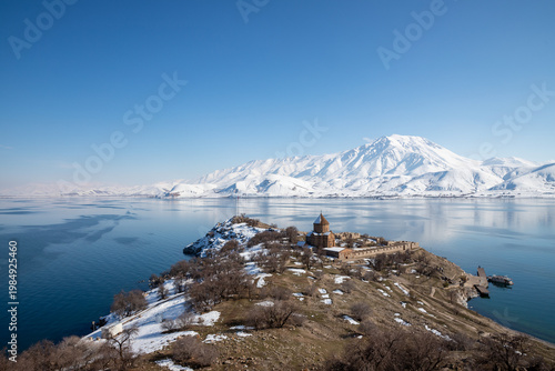 View of Akdamar Island with Holy Cross Church, Lake Van and snow-covered mountains, highlighting cultural heritage and winter landscape in eastern Türkiye