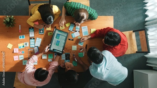 Top view of skilled software developer working together to develop Ux Ui design for mobile phone interface. Programmer sharing develop plan while looking at wireframe prototype icon. Convocation.