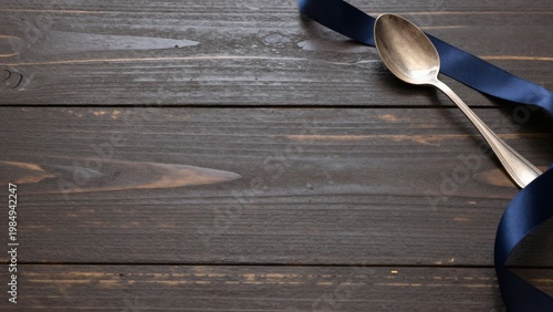 Vintage Silver Spoon and Navy Blue Ribbon on Dark Rustic Wooden Table with Copy Space