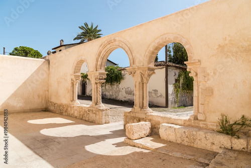 Wallpaper Mural The cloister of the Catacombs of San Giovanni in Syracuse, Sicily, Italy. Historic religious courtyard featuring stone arches and medieval architecture. Torontodigital.ca
