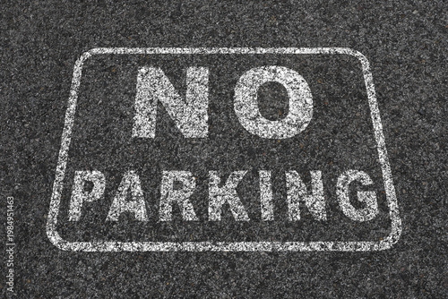 design on a dark asphalt. The text reads 'NO PARKING' in bold, capital letters
