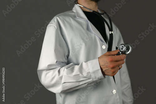 A doctor holds a stethoscope in his right hand ready for usage