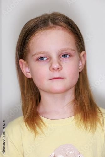 Studio portrait of a serious young blonde girl wearing a yellow shirt