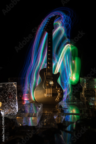 Music Concept: Guitar Miniature on a Dark Background with Vivid Light, Smoke, and Fire Effects. Golden electro guitar under a Dramatic Spotlight.
