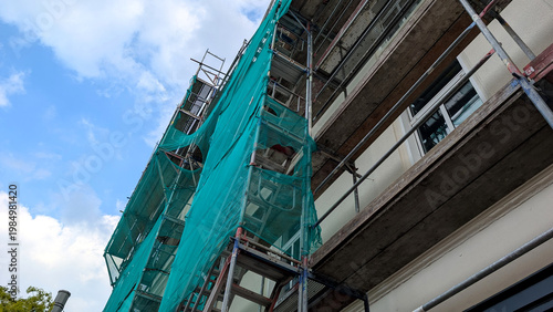 Metal scaffolding on a gray building facade during renovation. Exterior construction work, maintenance and restoration concept. 