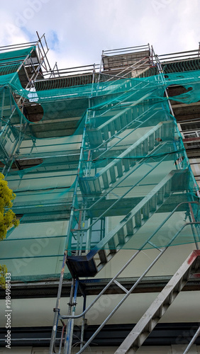 Metal scaffolding on a gray building facade during renovation. Exterior construction work, maintenance and restoration concept. 