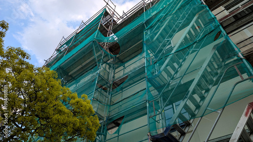 Metal scaffolding on a gray building facade during renovation. Exterior construction work, maintenance and restoration concept. 