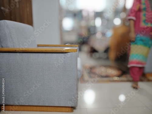 Close-up of a room's interior focusing on a sofa. The sofa has a light gray fabric upholstery with a wooden frame and armrest.
