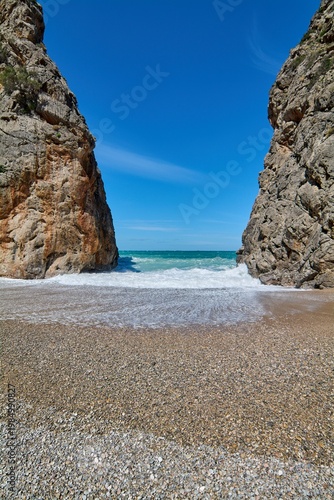 Mediterranean coastal canyon with crashing waves on a pebble beach providing a natural frame for travel and tourism marketing concepts