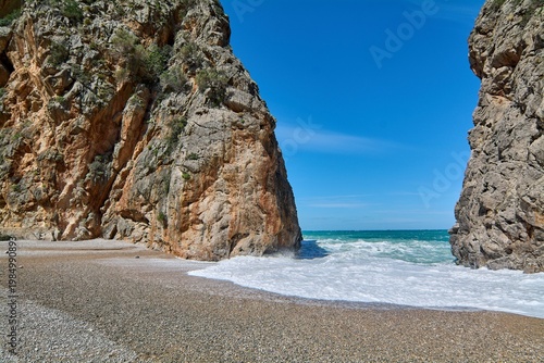 Rocky canyon opening to the turquoise sea at a famous coastal destination for tourism and nature photography.
