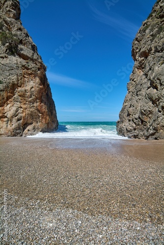 Scenic coastal gorge opening to a wild beach with crashing sea waves. Famous natural landmark in Europe for Mediterranean vacation advertising and travel brochures. Spectacular seaside scenery