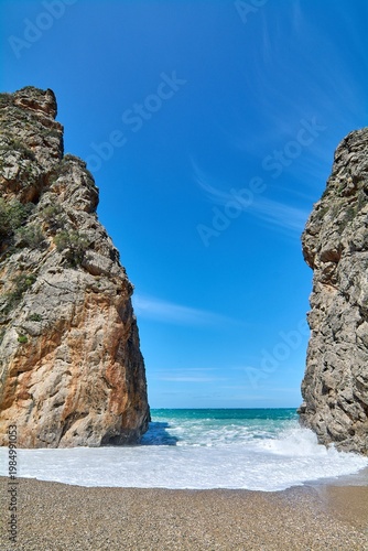 Dramatic coastal gorge with crashing Mediterranean waves on a natural stone beach. Iconic European landmark for vacation advertising and tourism brochures. High quality seaside landscape. Copy space.