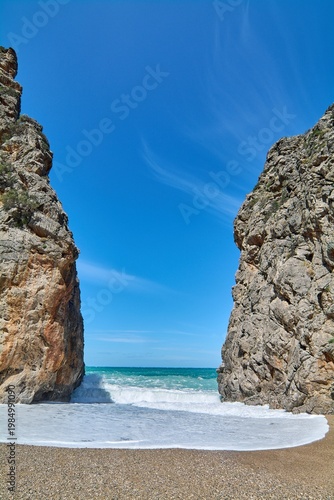 Scenic coastal gorge opening to a natural stone beach with crashing sea waves. Famous European landmark for Mediterranean travel marketing and vacation advertising campaigns. Spectacular scenery.