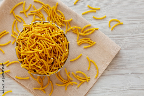 Organic Dry Raw Macaroni Pasta in a Bowl, top view. Copy space.