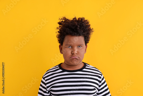 фотографія Portrait of resentful little boy on yellow background