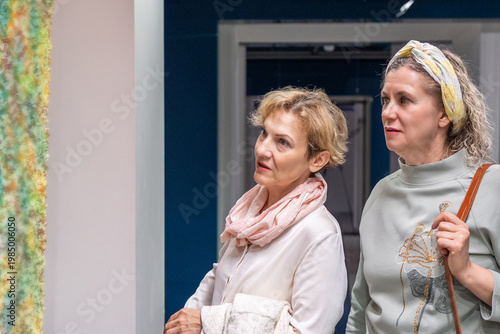 Two Women Viewing Art Exhibition In Gallery 