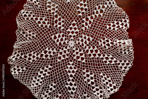 Top view of round crochet lace doily on wooden surface