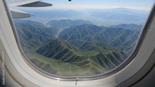 Jet Window Perspective Crossing Green Mountain Ranges With Valleys and Ridges Stretching Into Distance
