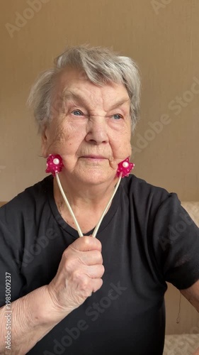 Elderly woman neck massage red roller tightening double chin close-up, pink twin rollers gliding along jaw and neck, seated at home.