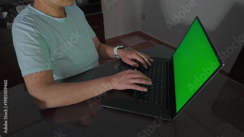 Woman Typing on Laptop with Green Screen for Easy Content Integration