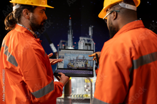 Photos Offshore platform crew staff members checking equipment status indicators on laptop system dashboard