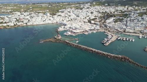 Aerial drone view of Naousa village on Paros island, Greece, showing traditional white buildings, coastal harbor and clear blue sea in daylight. Ideal for travel, tourism and Mediterranean lifestyle 