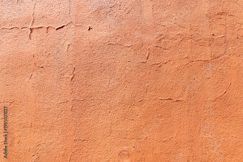 Orange textured wall with peeling paint. Terracotta colored stucco wall background