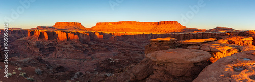 This scenic panorama of Canyonlands National Park features the sun's warm first light illuminating the Island in the Sky and reaching Monument Basin.