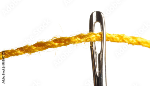 A vibrant yellow thread is carefully guided through the eye of a shiny silver sewing needle. Available in transparent background.