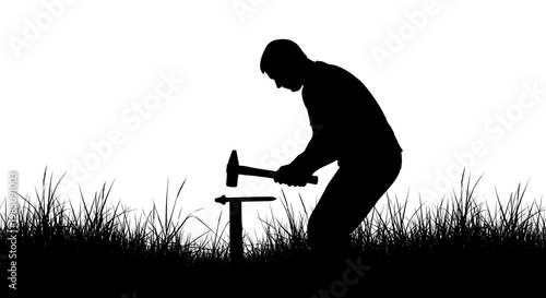 A black silhouette of a man hammering a stake into the ground in a field of grass
