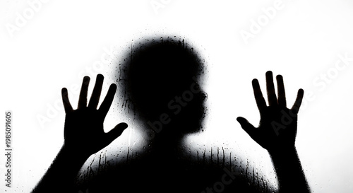 A silhouette of a person pressing their hands against a white background
