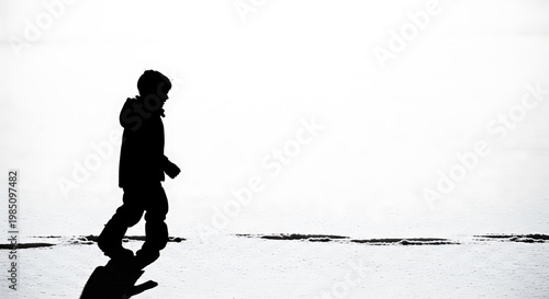 A silhouette of a person walking alone on a beach with a serene and peaceful atmosphere