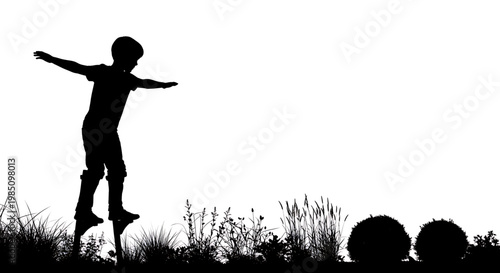 A silhouette of a young boy playing on a pogo stick in a field of grass and flowers