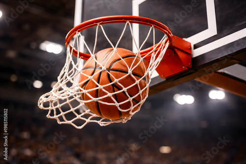 Basketball going through hoop net inside indoor arena during game action